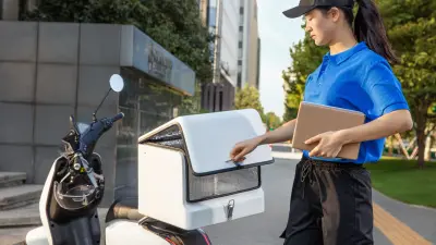Female delivery driver closing a scooter mounted box.