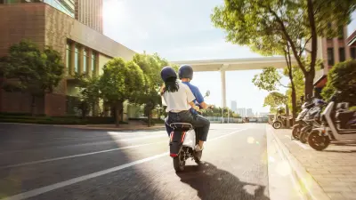 Woman riding at the back of a scooter with a professional driver.