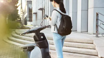 Woman unlocking a shared electric scooter with a mobile app.